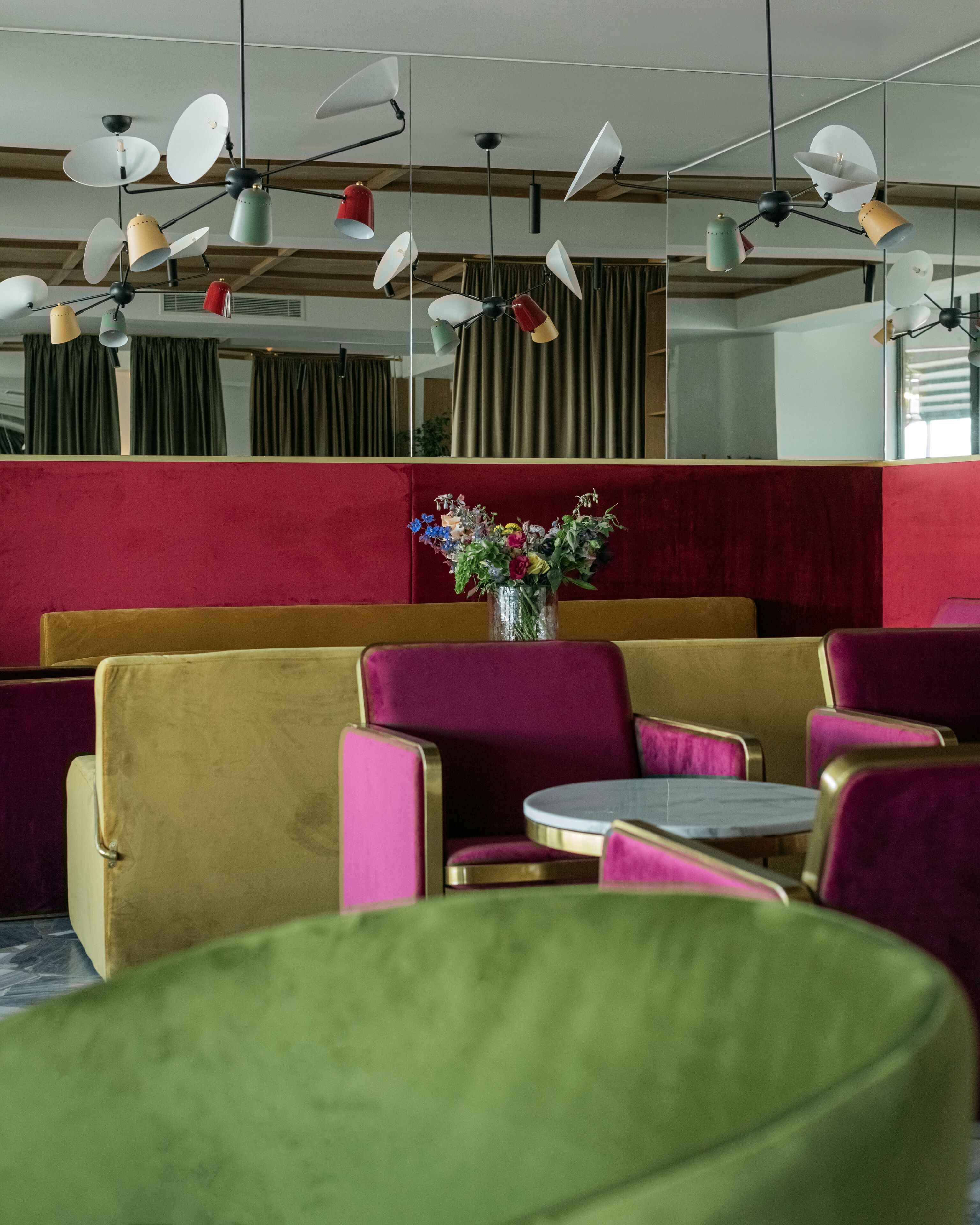 A seating area with booths and tables, a vase with flowers, and ceiling fans.