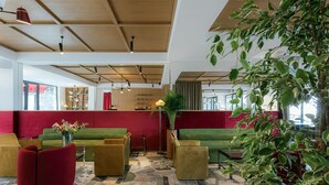 A modern lobby with green sofas, red chairs, and a stone-tiled floor. - Castor & Pollux Hotel (Tbilisi)