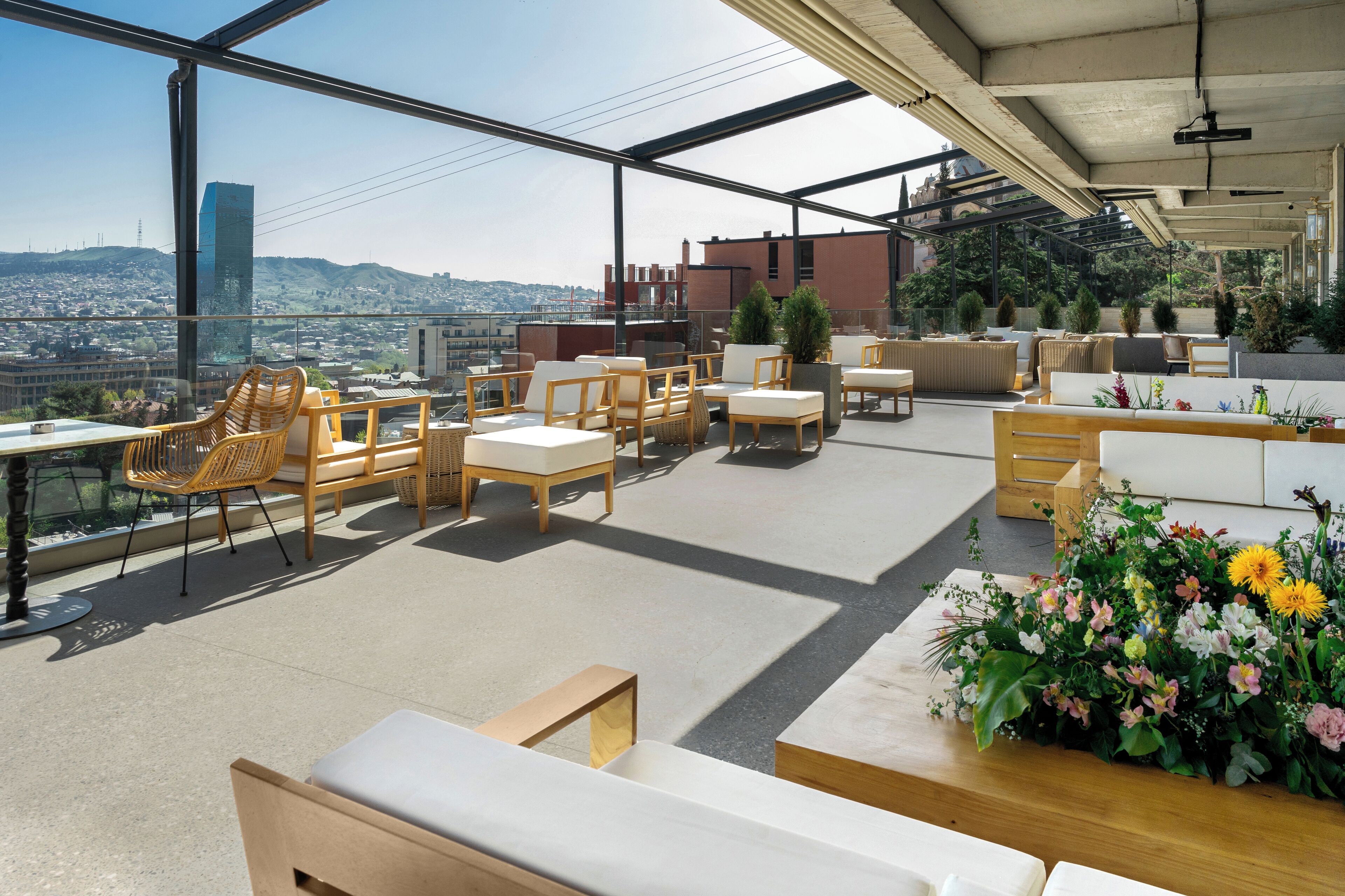 Una terrazza panoramica con zone relax, vista sulla città e piante in vaso.