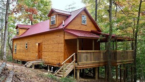 A log cabin with a wooden deck and a staircase leading to the entrance.