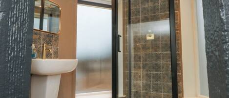 A bathroom with a glass-enclosed shower, a sink, and a toilet.