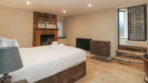 A bedroom with a bed, a fireplace, a radiator, and a staircase leading to an outdoor area.