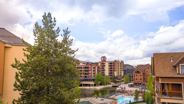 Ein Hotel mit Pool, einem Fluss und einem Kirchturm im Hintergrund.
