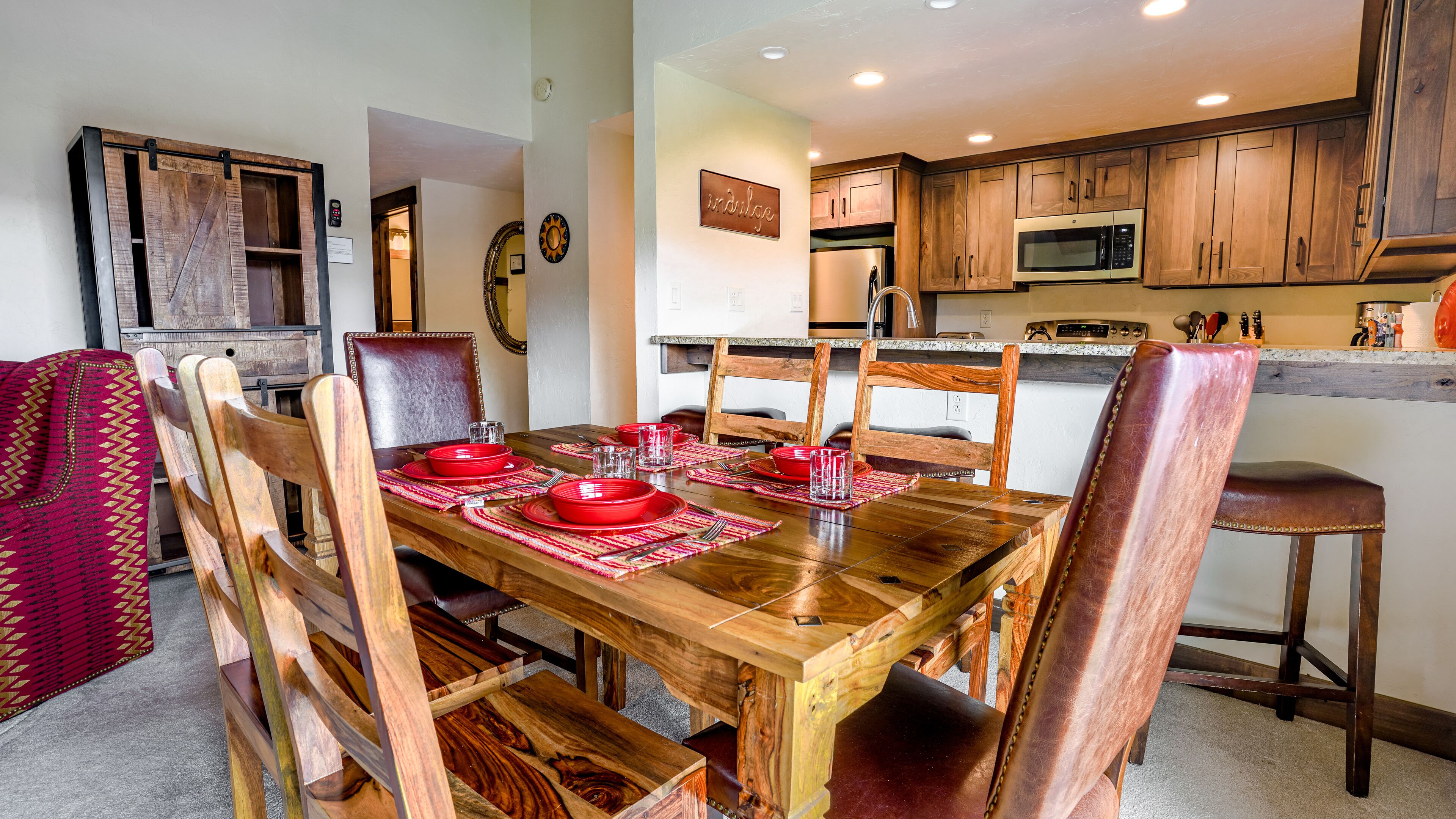 Un coin repas avec une table en bois dressée pour six personnes, entourée de chaises en bois.