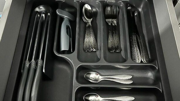 A drawer with various utensils neatly organized in compartments.