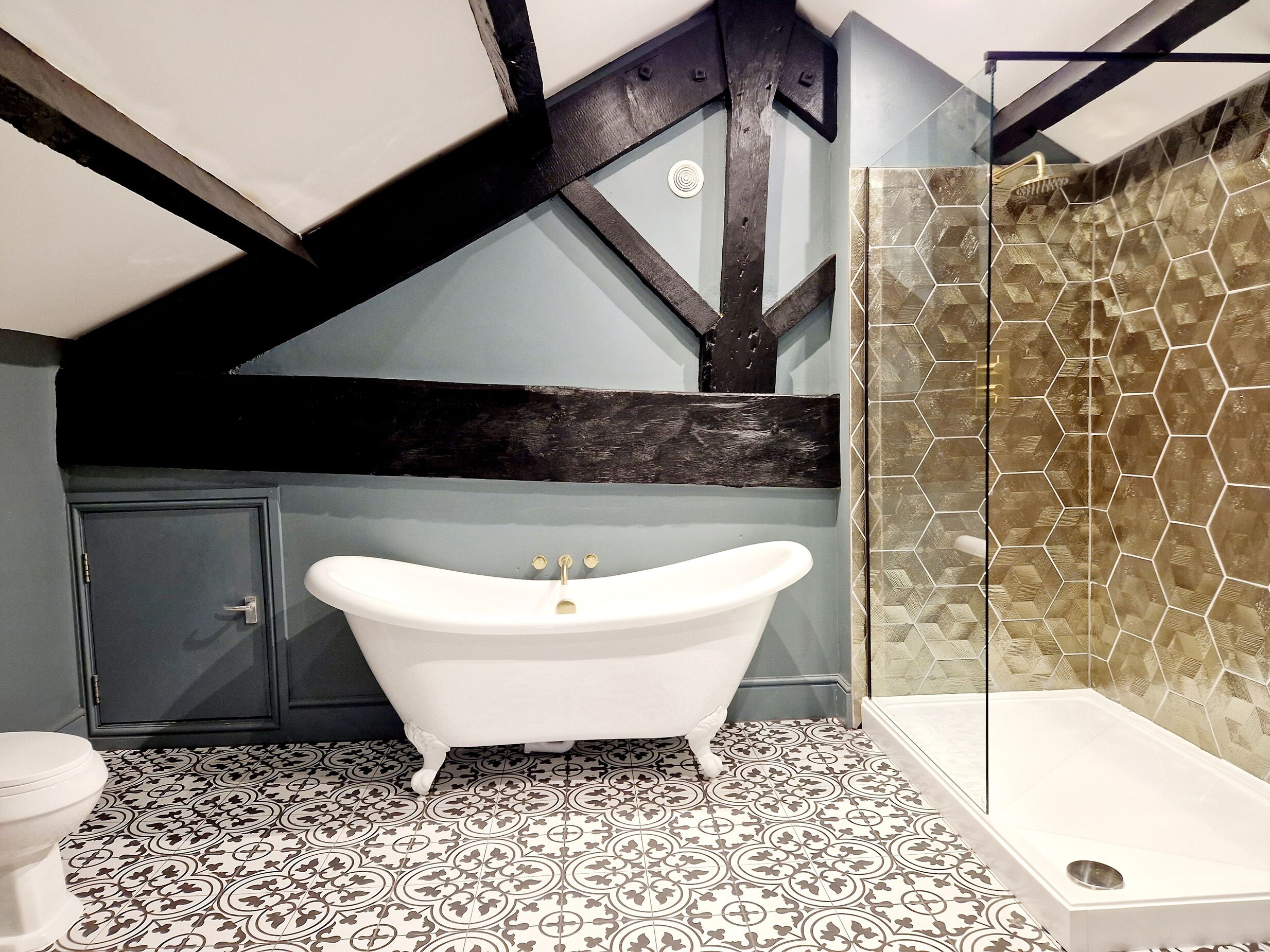 A bathroom with a freestanding bathtub, a shower enclosure, and patterned floor tiles.