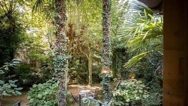 A lush garden with a stone staircase leading to a seating area.