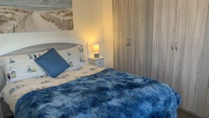 Makuuhuoneessa on sänky, yöpöytä, lamppu, vaatekaappi ja seinällä taulu.