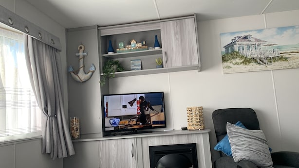 Olohuone, jossa on televisio, takka ja rannasta inspiroitunut taulu.