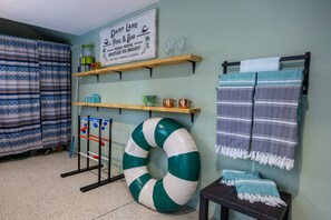 A room with a pool float, shelves with mugs and glasses, a sign reading "Daisy Lane Pool & Bar," and a striped towel on a rack. - Central location | Hot Tub | Heated Pool | Digital Game Table (Normal)