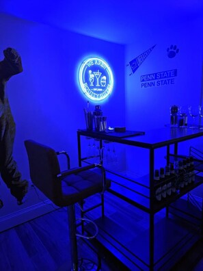 Eine Barbereich mit einer Neonreklame, einem Penn State-Logo und einer Theke voller Flaschen.