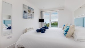 Une chambre dotée d’un grand lit, d’un téléviseur à écran plat et d’une fenêtre donnant sur l’extérieur.