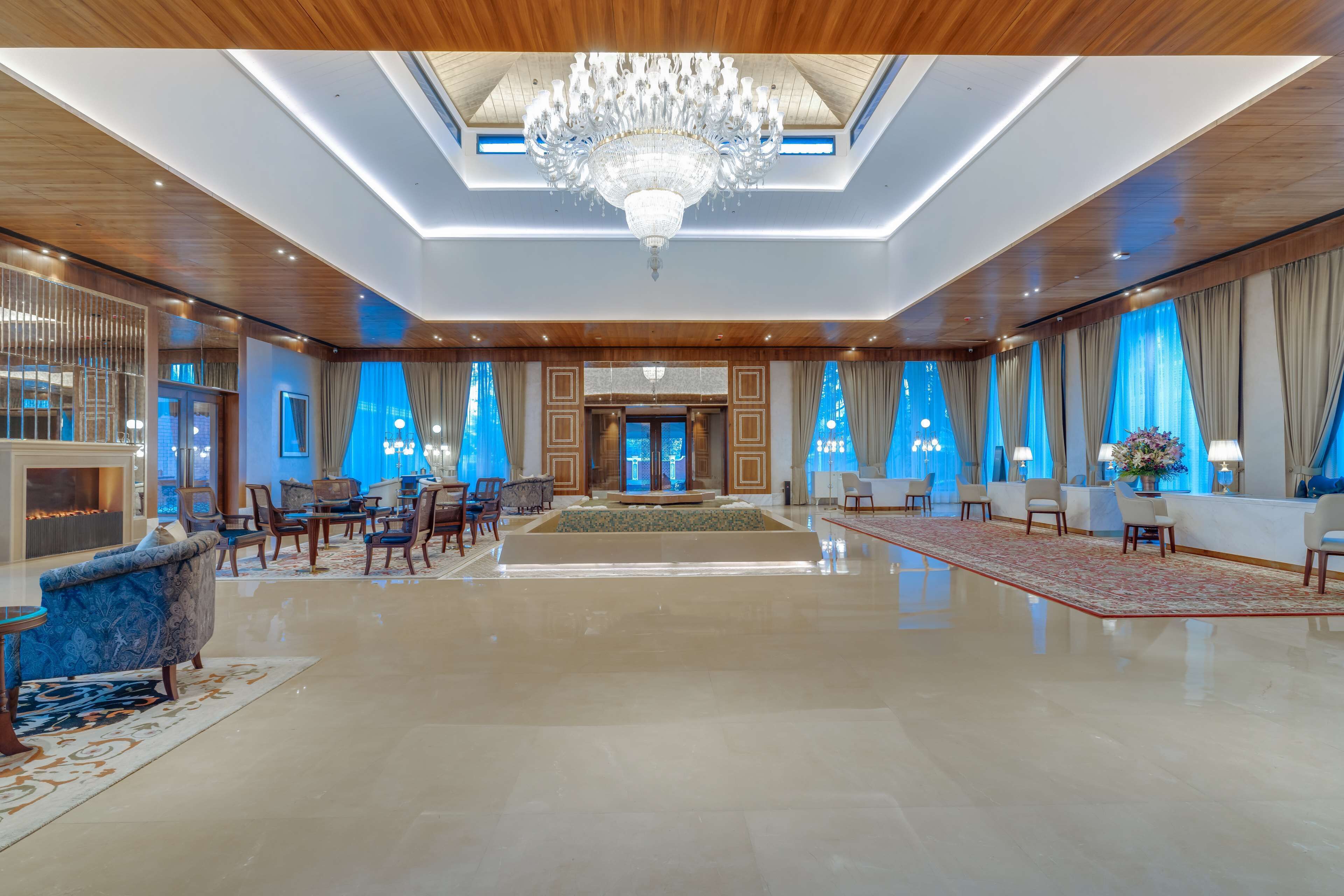 A spacious lobby with a chandelier, seating area, and a reception desk.
