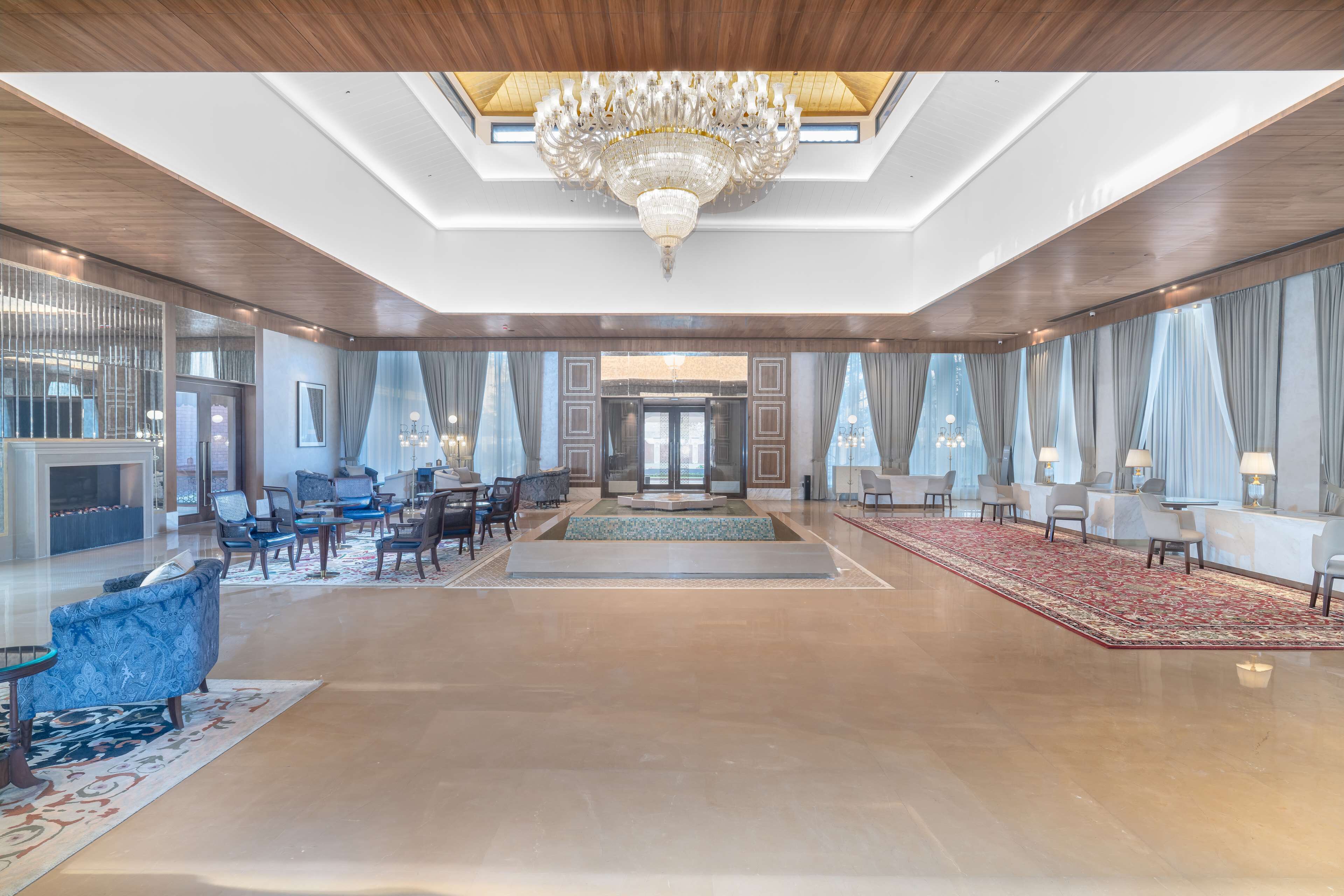 A spacious lobby with a grand chandelier, seating areas, and large windows.