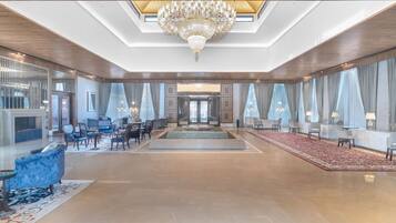 A spacious lobby with a grand chandelier, seating areas, and large windows.