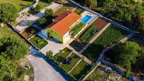 Vista aérea de una propiedad con un edificio amarillo, una piscina y campos verdes.