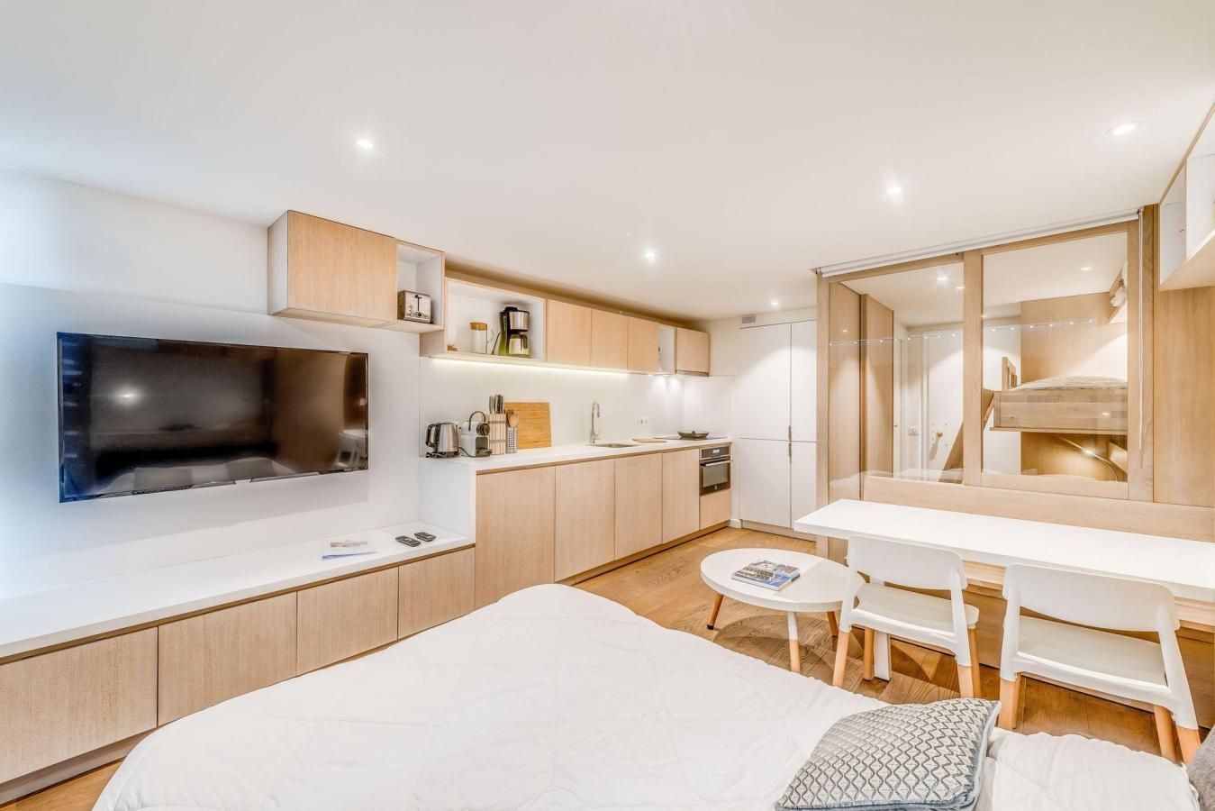 A modern bedroom with a bed, bedside table, and a TV mounted on the wall.