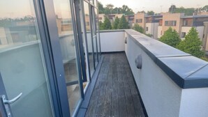 A balcony with a wooden floor, glass doors, and a view of neighboring buildings. - Impeccable 2 Bed 2 Bath Penthouse (London)