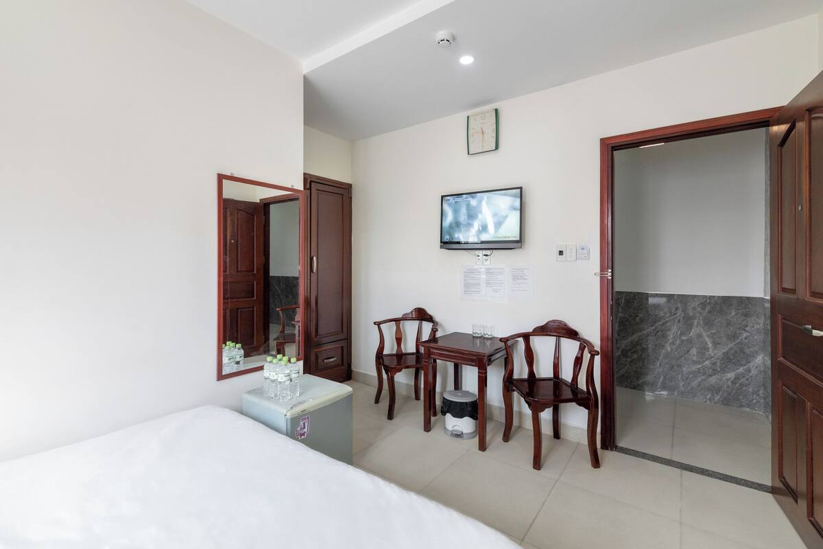 Une chambre d’hôtel comprenant un lit, un bureau avec des chaises, une télévision et une porte donnant accès à une salle de bain.