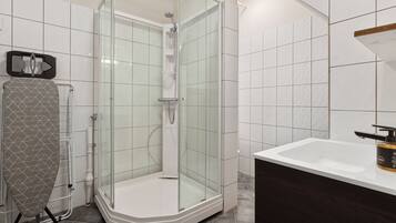 A modern bathroom with a glass-enclosed shower, a white sink, and a towel rack.