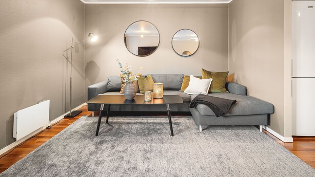 A modern living room with a grey sofa, a coffee table, and two round mirrors on the wall. - Amalie Apartments By First (Tromsø)