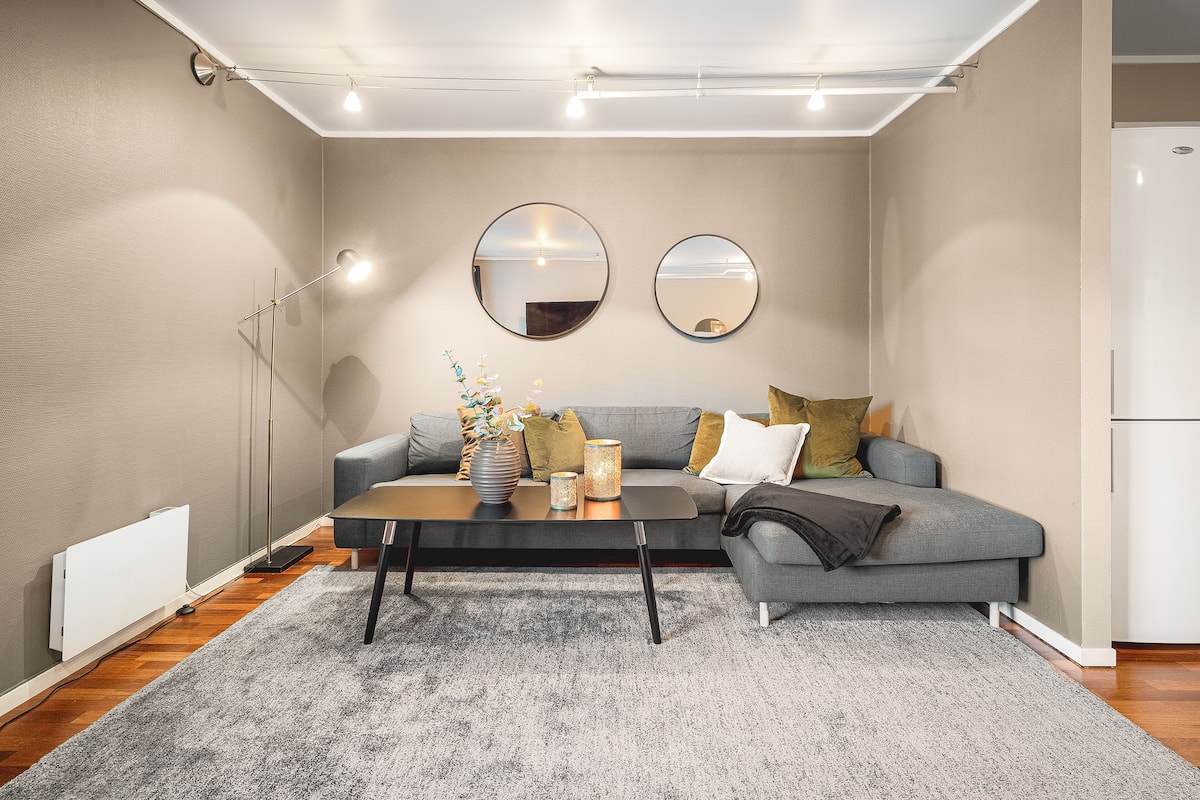 A modern living room with a grey sofa, a coffee table, and two round mirrors on the wall.