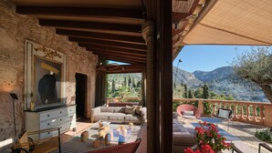 A cozy outdoor seating area with a sofa, chairs, and a hammock. A large vase with flowers is visible in the foreground. - Valldemossa Hotel (Valldemossa)