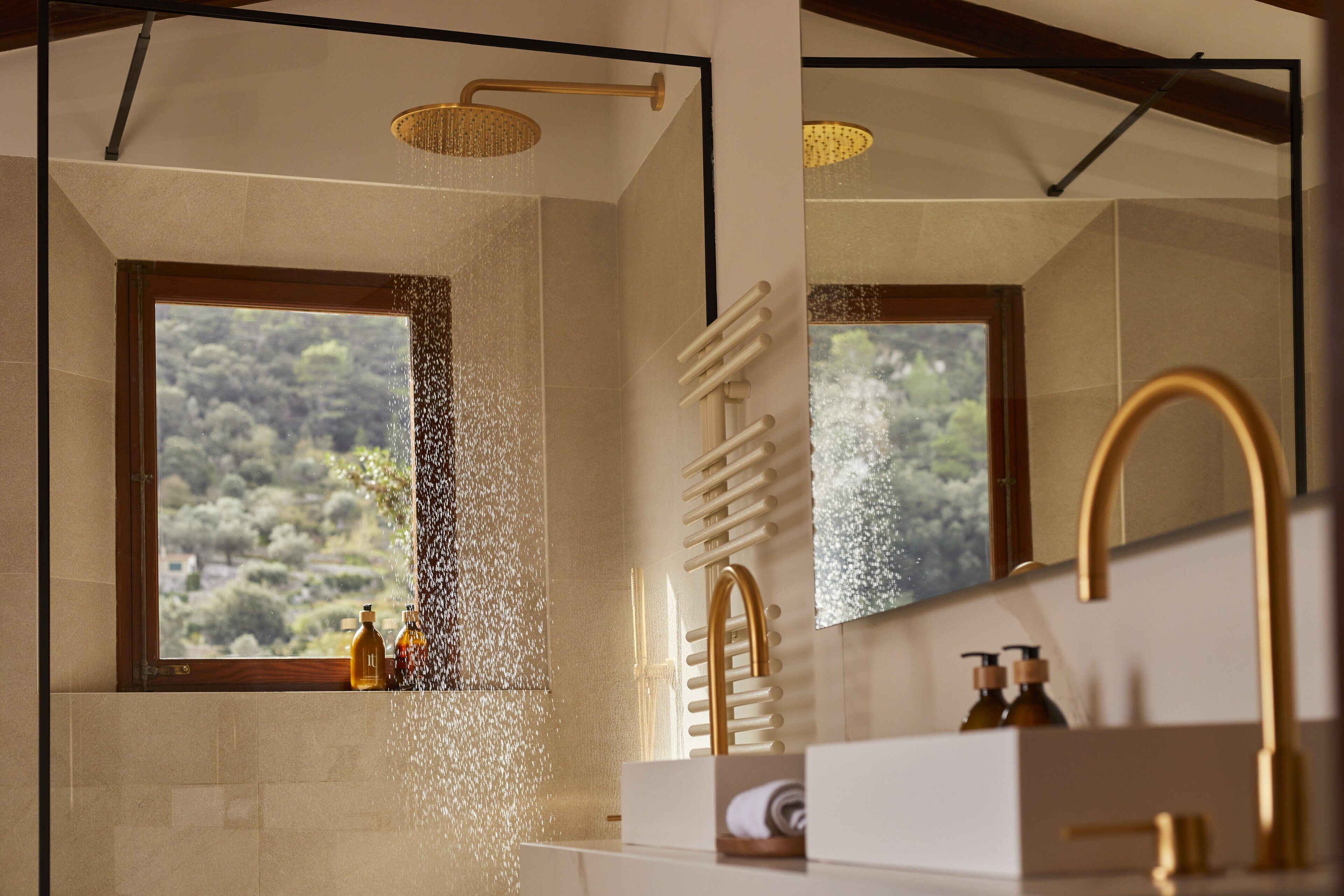 Un baño moderno con ducha, un ventanal grande y un espejo que refleja la vista.