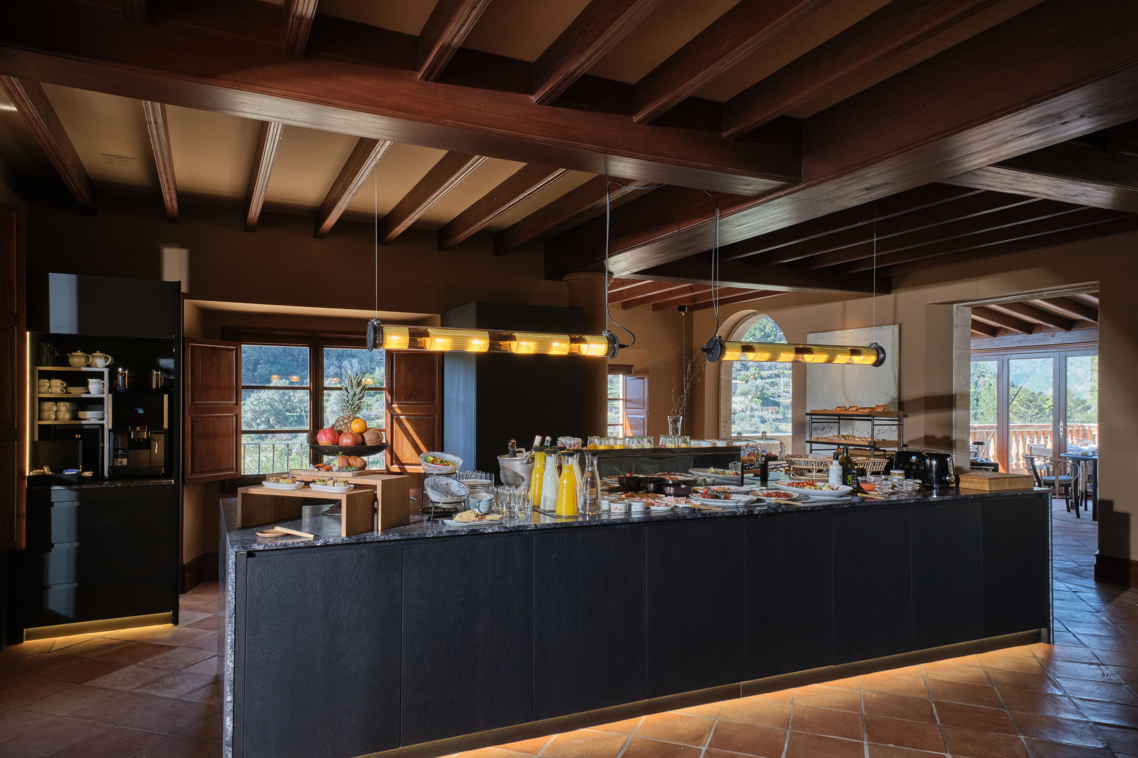 Una cocina amplia con una isla grande, vigas de madera y ventanas espaciosas.