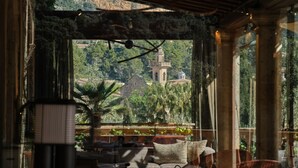 A cozy room with a large window overlooking a lush garden and a distant tower. - Valldemossa Hotel (Valldemossa)