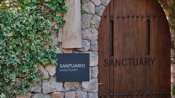 A stone wall with a wooden door labeled "Santuario Sanctuary" and a signboard.