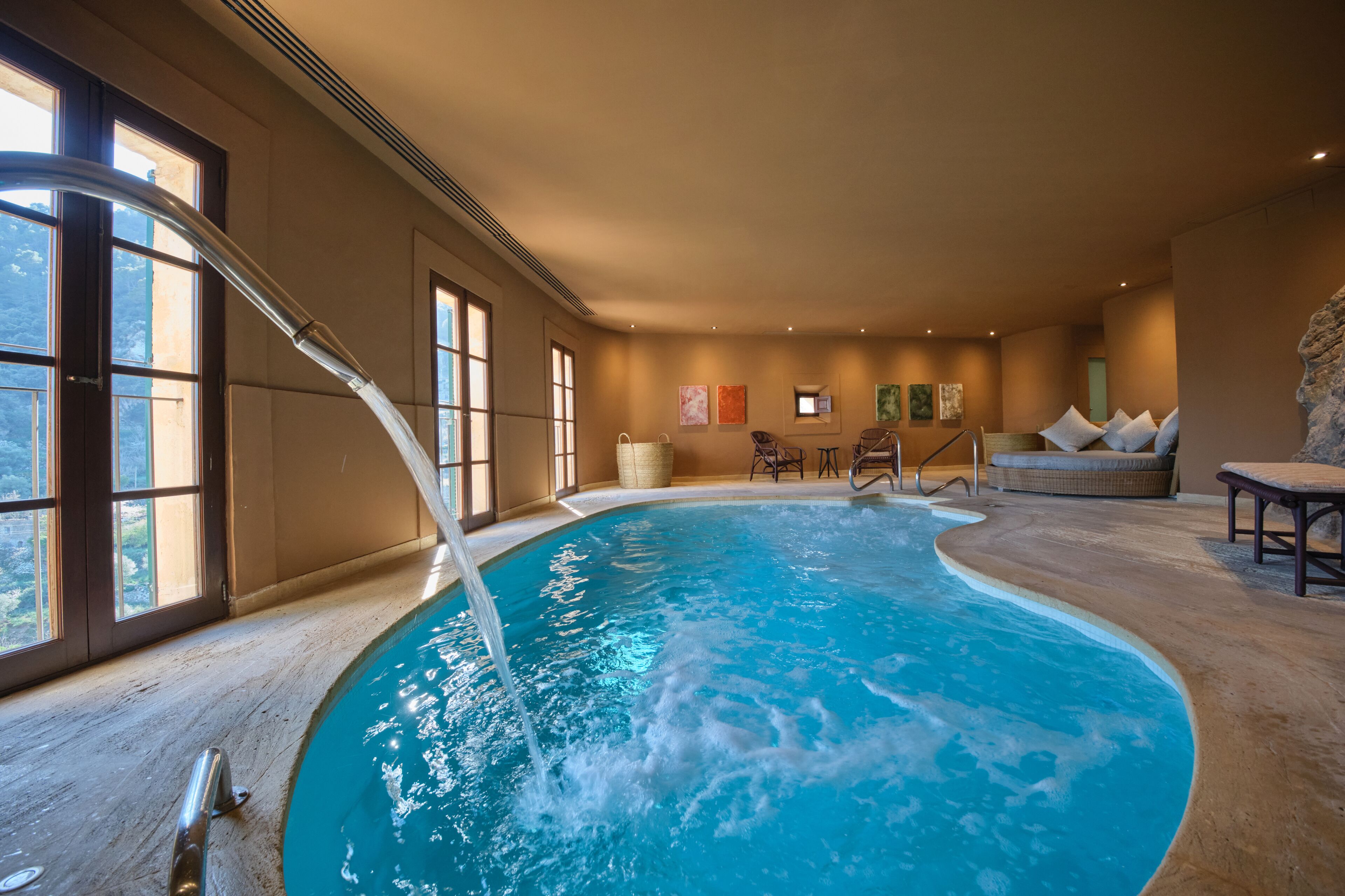 Piscina interior com vista clara dos arredores, incluindo assentos e uma parede de pedra.