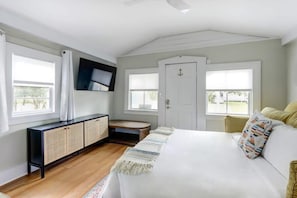 A bedroom with a bed, a TV mounted on the wall, a wardrobe, and a window with curtains.