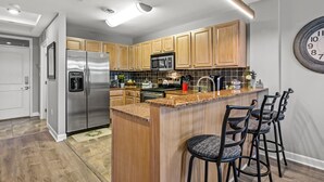 Una cocina moderna con armarios de madera, electrodomésticos de acero inoxidable y encimera de granito.