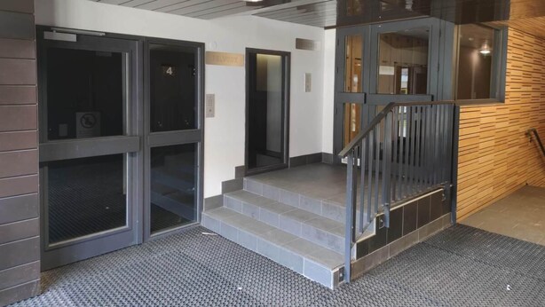 Un interior moderno con una escalera, una puerta con la etiqueta “4” y una cámara de seguridad en el techo.