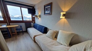 Una habitación acogedora con sofá cama, una mesita y televisor.