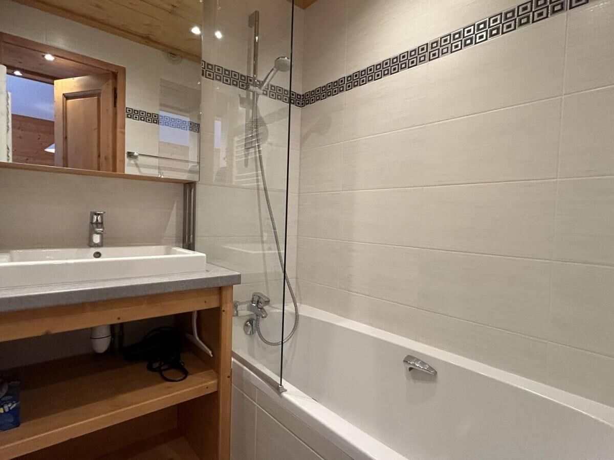 A bathroom with a sink, mirror, and shower.