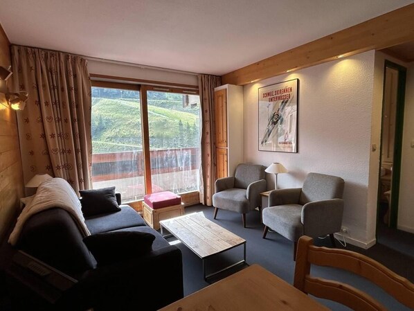 A cozy room with a wooden ceiling, a sofa, two armchairs, a small table, and a window with a view of greenery. - 90m from ski slopes, 1st floor, view ski slopes, balcony, 37m², Méribel-Mottaret (Méribel - Les Allues)