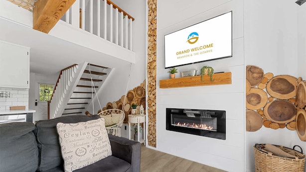 Een moderne woonkamer met een open haard, een tv aan de muur en een trap.
