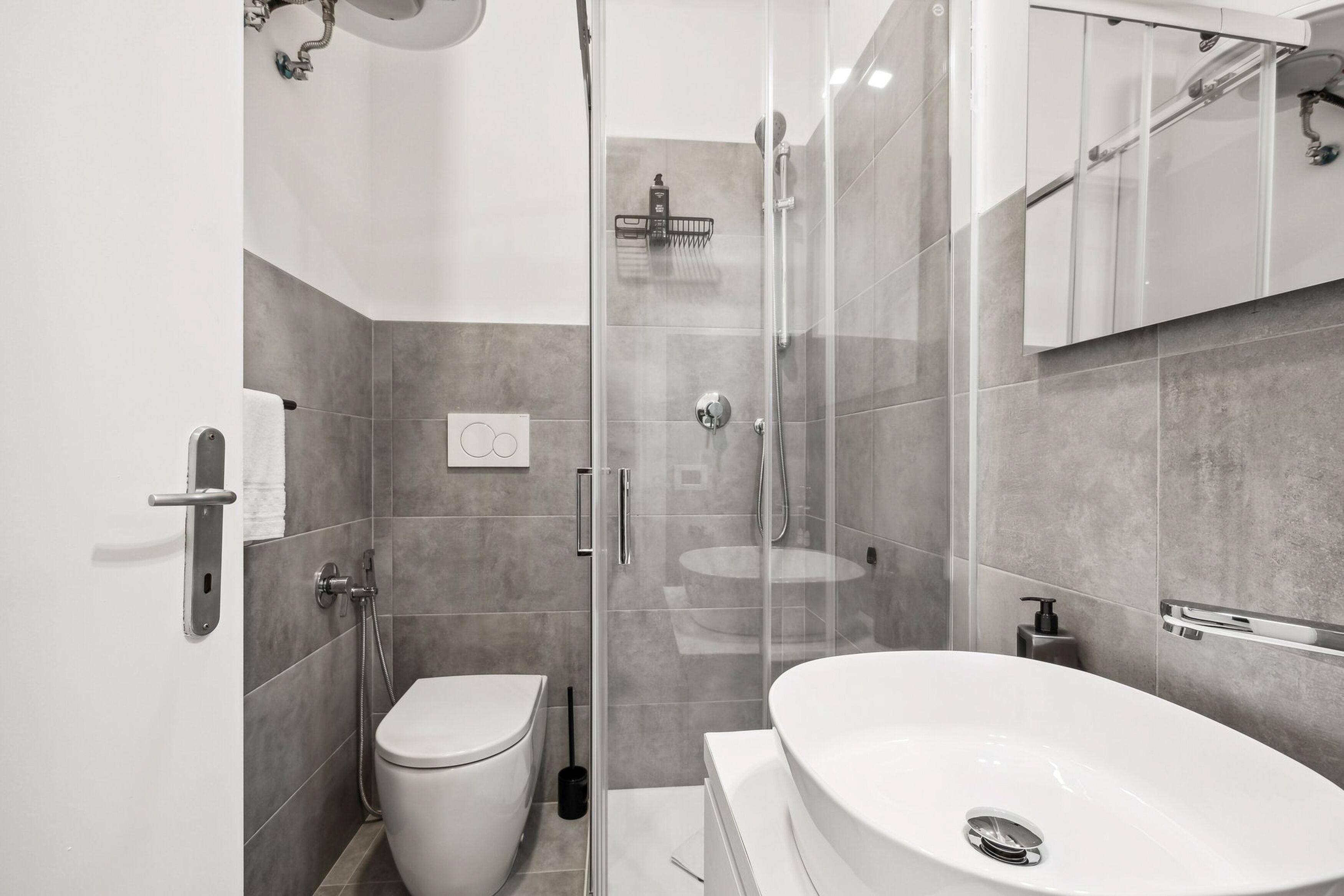 A modern bathroom with a glass-enclosed shower, a white toilet, and a large white sink.