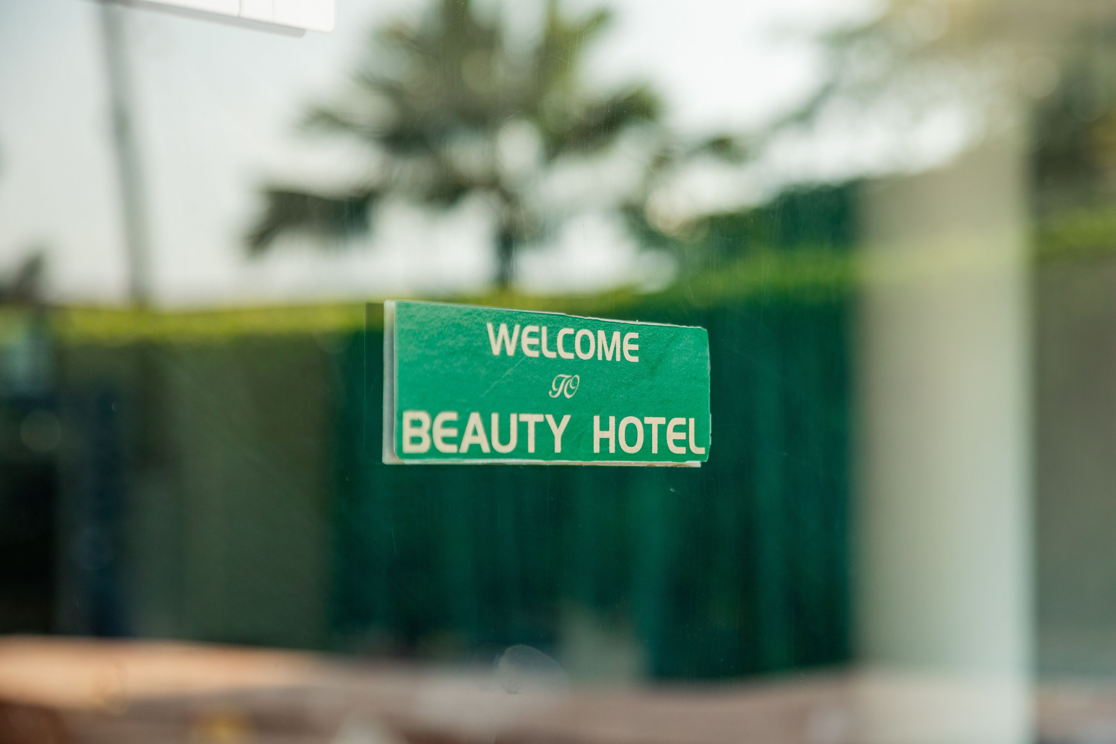 A green sign with white text that reads "WELCOME TO BEAUTY HOTEL".