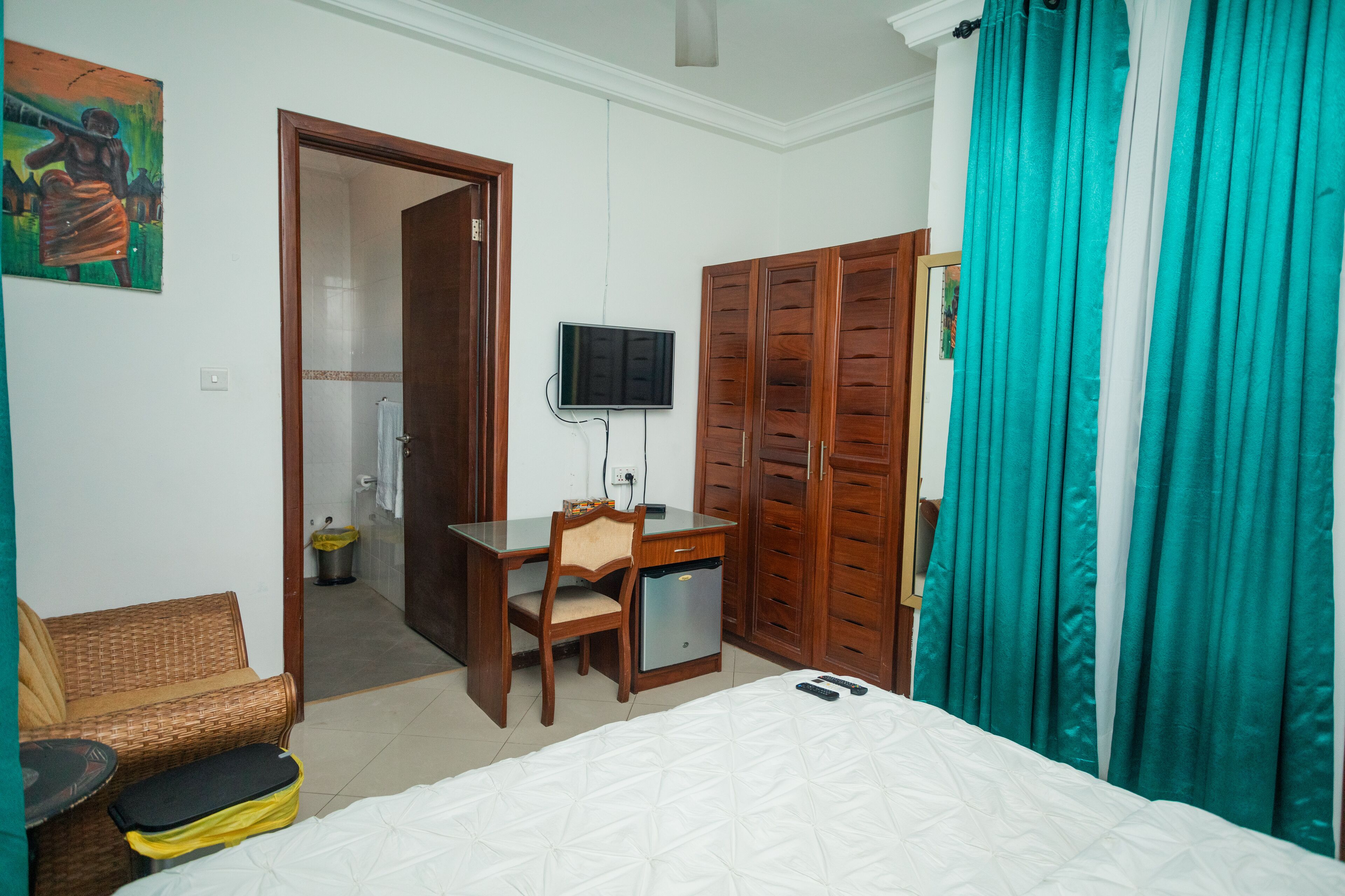A hotel room with a bed, a desk with a chair, a television, and a wardrobe.