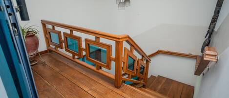 Eine Holztreppe mit einem geometrischen Geländerdesign, die zu einer oberen Etage führt.