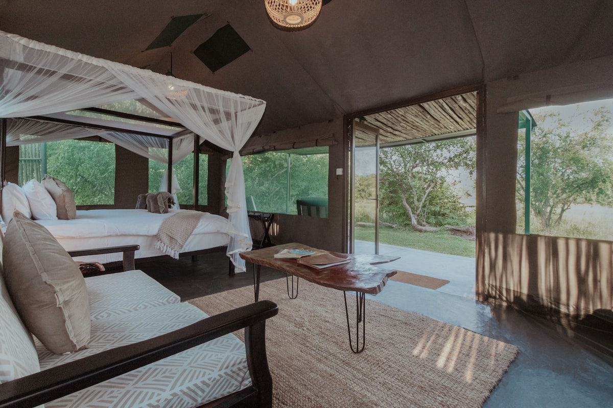 Un dormitorio con cama, mesita de noche y vistas al exterior.