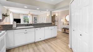 A modern kitchen with white cabinets, a granite countertop, and a built-in stove.