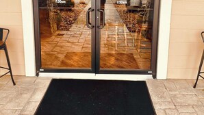 A Starbucks entrance with a glass door, a black mat, and a reflection of the interior.