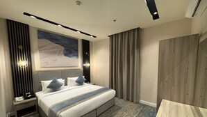 Une chambre d’hôtel moderne avec un grand lit, une table de chevet, un bureau et une armoire.