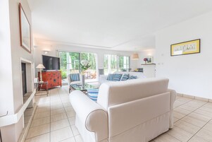 Un salon spacieux comprenant un canapé, un téléviseur et un coin repas avec des chaises et une table.