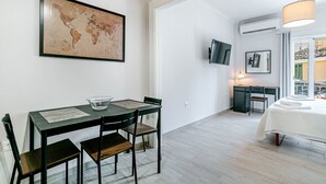 A modern room with a dining table, chairs, a world map artwork, a TV, and a bed with a white bedspread. - Alex Home by Corfuescapes (Corfu)