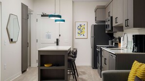Een moderne keuken met een centraal eiland, barstoelen en een eethoek.